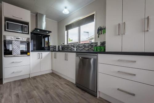 a kitchen with white cabinets and stainless steel appliances at Beez Kneez in Rotorua
