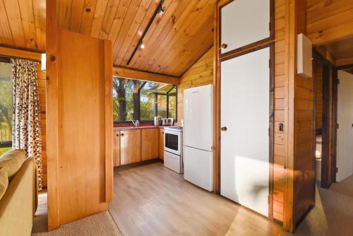 a kitchen with a white refrigerator and wooden walls at Cooper's Lakeside Cabin in Rotorua