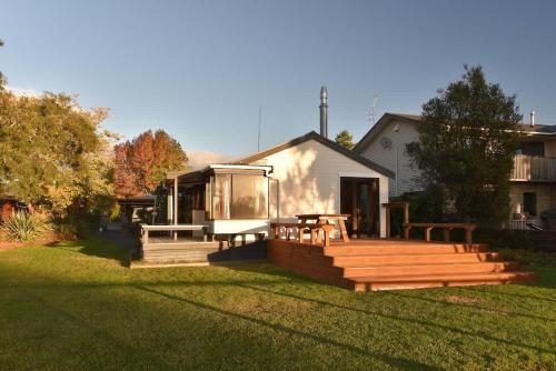 a house with a large deck with benches in the yard at Cooper's Lakeside Cabin in Rotorua