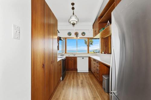 a kitchen with wooden cabinets and a large window at Hannah's Bay Lakefront in Rotorua