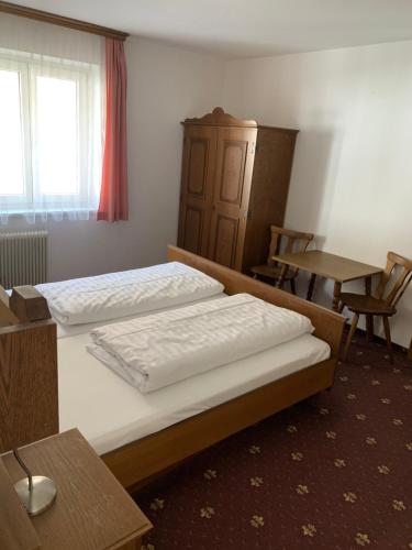 a bedroom with two beds and a table and a window at Pension Plattenhof in Telfs