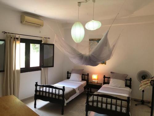 two beds in a room with two lamps and a window at La Maison tout confort au bord de la mer in Niaga