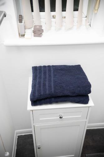 a blue towel sitting on top of a white dresser at Emerald Apartments A star Proximity in London