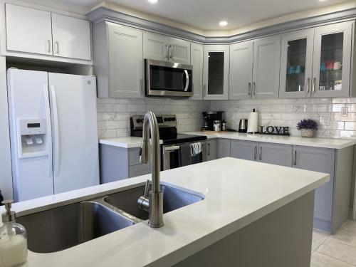 a white kitchen with a sink and a refrigerator at Victoria Family Vacation Home - King Bed Private Yard BBQ Deck Gazebo - 4 Minutes To The Falls in Niagara Falls