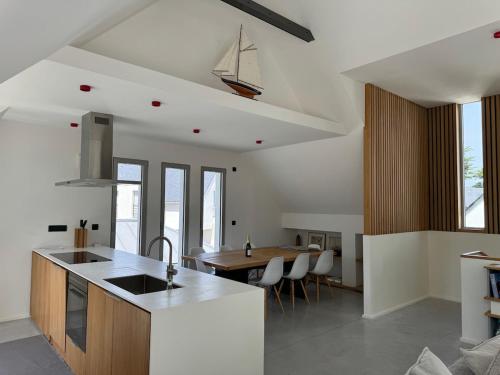 une cuisine avec un évier et une table avec des chaises dans l'établissement Villa contemporaine vue mer - Maison d'architecte, au Pouliguen