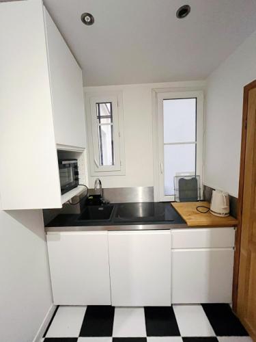 une cuisine avec des armoires blanches, un évier et une fenêtre dans l'établissement Stylish and bright apartment 35m2 Paris 11ème, à Paris