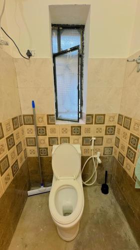 a bathroom with a toilet and a window at Patna Backpackers in Patna