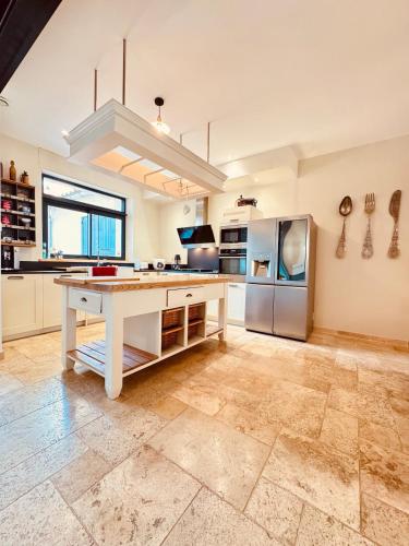 Il dispose d'une grande cuisine avec une table et un réfrigérateur. dans l'établissement À 1min d'une base nautique Maison spacieuse avec piscine, à Puicheric