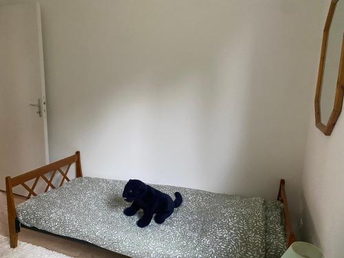 a black dog sitting on top of a bed at Gîte la clé des champs in Bueil
