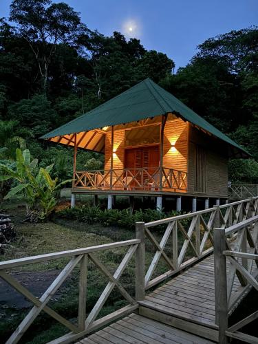 a wooden house with a green roof and a wooden bridge at Jenené Lodge Nuquí in Nuquí