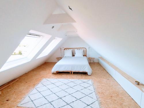 - une chambre mansardée avec un lit et une fenêtre dans l'établissement Maison avec vue mer à Saint-Pol-de-Léon, à Saint-Pol-de-Léon