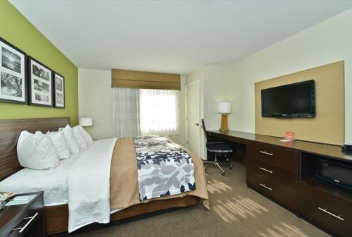 a hotel room with a bed and a desk and a television at Sleep Inn & Suites Harrisburg - Hershey North in Harrisburg