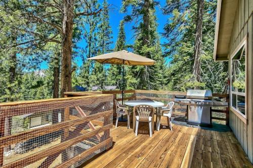 a wooden deck with a table and an umbrella at Bear Haus - Sledding At Cabin - Forest Views - Foosball in South Lake Tahoe