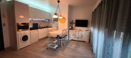 a kitchen with a table and a washing machine in it at Monte Gordo T1 Parque dos Reis in Monte Gordo