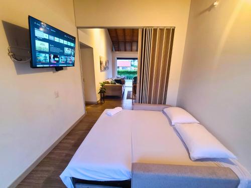 a large bed in a room with a flat screen tv at Casa Campestre en zona exclusiva con Jacuzzi, a 10 min del aeropuerto, 20 min parque del café, WiFi, parqueadero privado, vigilancia 24 hrs y amplias zonas sociales in Armenia