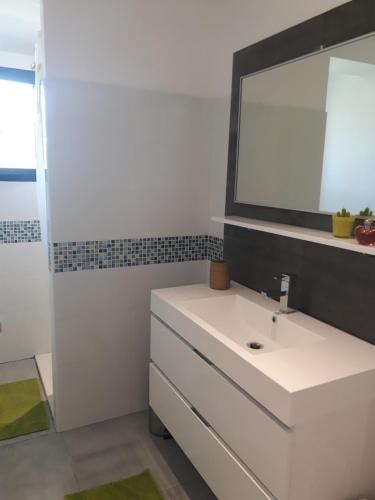 une salle de bain avec un lavabo blanc et un miroir dans l'établissement Gite cure thermale Jonzac, à Antignac