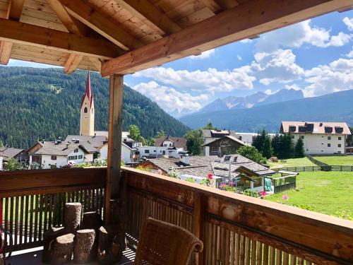 ein Balkon mit Blick auf eine Stadt und eine Kirche in der Unterkunft Luxury panoramic apartment Plan de Corones in Welsberg-Taisten
