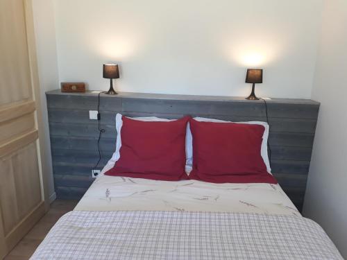 - un lit avec 2 oreillers rouges et 2 lampes au-dessus dans l'établissement Gite cure thermale Jonzac, à Antignac