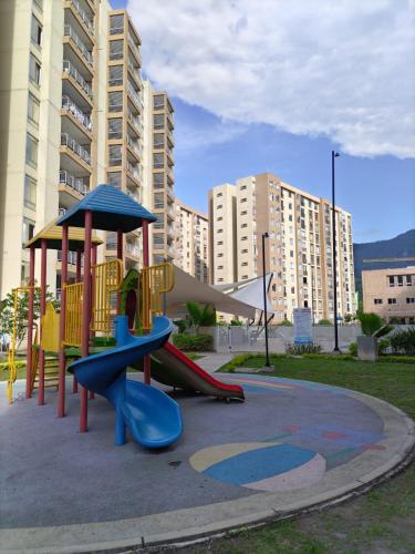 a playground with a slide in a park with tall buildings at Apartamento en Villeta Hermoso in Villeta