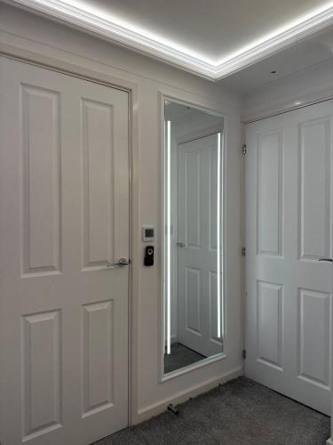 a room with two white doors and a mirror at Private Bedroom in Unique Luxury House, Salford, Manchester in Manchester