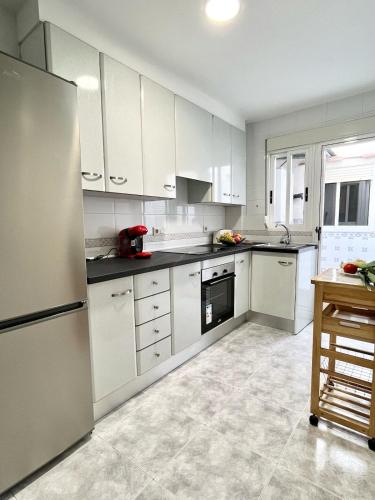 a kitchen with white cabinets and a refrigerator at Apartamentos de la Casa Ducal in Gandía
