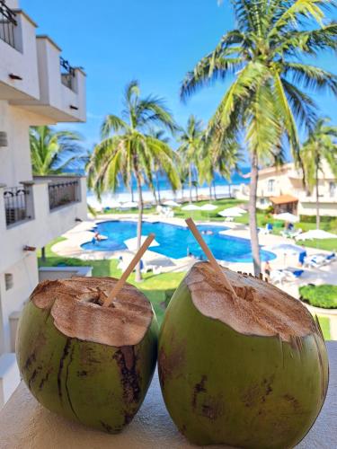 two coconuts sitting on a table near a resort at Apartamento familiar con vista espectacular al mar in Ixtapa