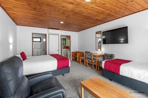 a room with two beds and a couch and a desk at Austria Motel in Paihia