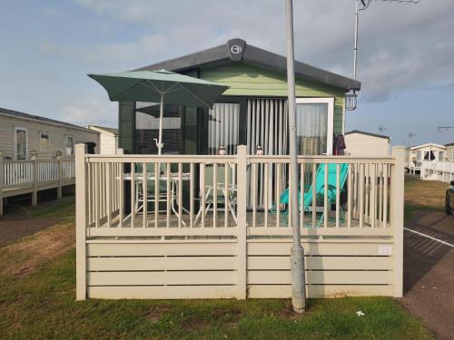 a gazebo with a table and an umbrella at Green House Moselle in Jaywick Sands