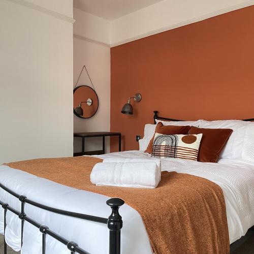 a bedroom with a large bed with orange walls at Shoreside - Beach Family Home in Exmouth