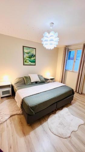 une chambre avec un grand lit et un lustre dans l'établissement L'escapade Vosgienne, à Cornimont