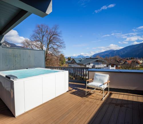 a deck with a hot tub and a chair on a balcony at PENTHOUSE N`1 - Stylish Apartment with Rooftop Whirlpool Access in Tyrol, presented by AlpenLuxus in Kramsach
