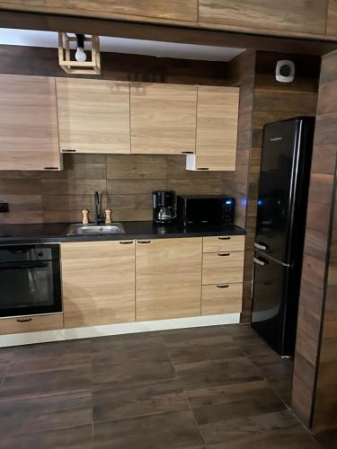 une cuisine avec des armoires en bois et un réfrigérateur noir dans l'établissement BY NEPTUNE - Appartement BALI Jacuzzi, à Boissy-Saint-Léger