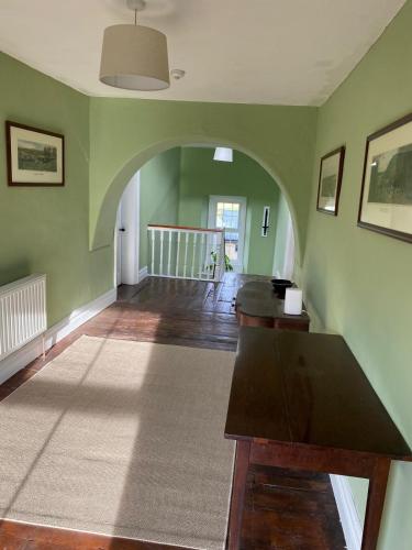 an empty living room with green walls and a wooden table at Farnagh House - En Suite Bedrooms in Moate