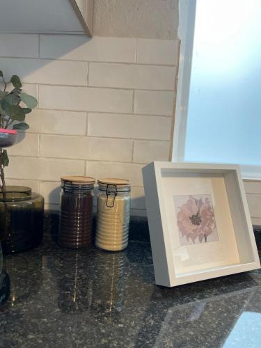 a picture and a picture frame next to three jars at Hermoso Departamento, WiFi, terraza vista al Lago de Pátzcuaro, elevador, free parking in Pátzcuaro