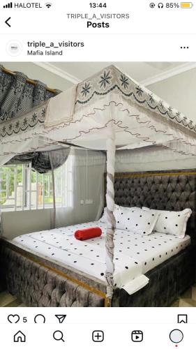 a white canopy bed with a red pillow on it at Triple A visitors in Kilindoni