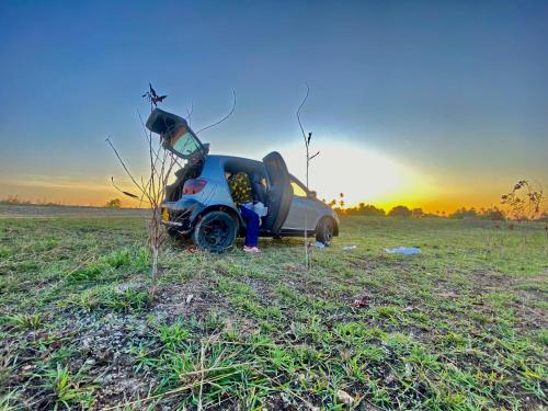 a motorcycle parked in a field with the sunset in the background at Triple A visitors in Kilindoni