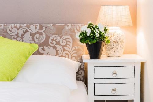 a bed with a nightstand with a lamp and a plant on it at Wildgrün Mini Lodge 8a in Pfronten