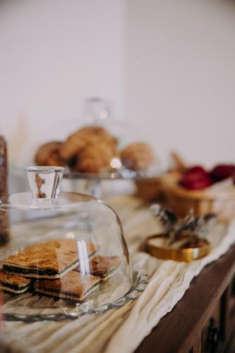 a wooden table topped with sandwiches and a glass container at Casa Emilia B&B with cocktail bar in Albinea