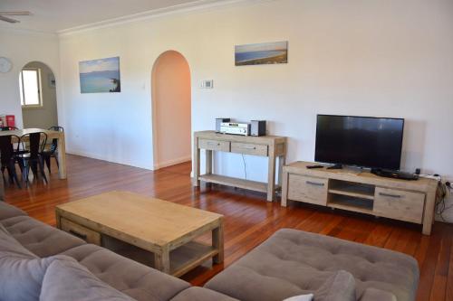a living room with a couch and a flat screen tv at Adacos 19 On Sturt - Bring your own linen in South West Rocks