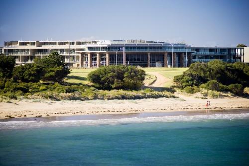 a building on the beach next to the ocean at Wyndham Resort Torquay in Torquay