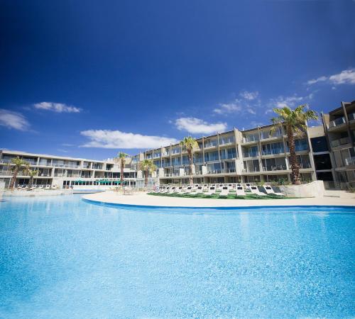 a resort with a large swimming pool with lounge chairs at Wyndham Resort Torquay in Torquay