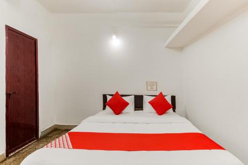 a bedroom with a white bed with red pillows at Super Hotel O Sushma Lodge in Manipala
