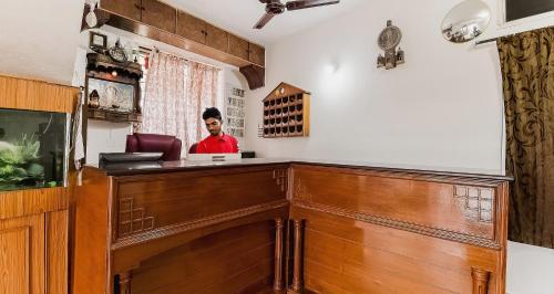a man is standing behind a counter in a salon at Super Hotel O Sushma Lodge in Manipala