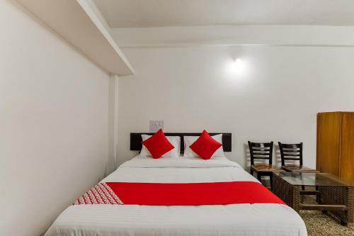 a bedroom with a bed with red pillows on it at Super Hotel O Sushma Lodge in Manipala