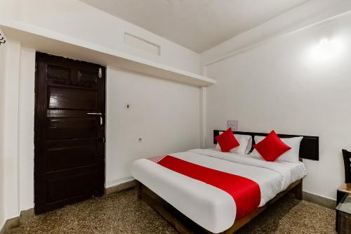 a bedroom with a large bed with red pillows at Super Hotel O Sushma Lodge in Manipala