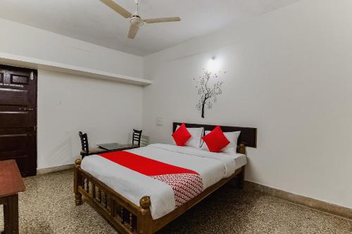 a bedroom with a large bed with red pillows at Super Hotel O Sushma Lodge in Manipala