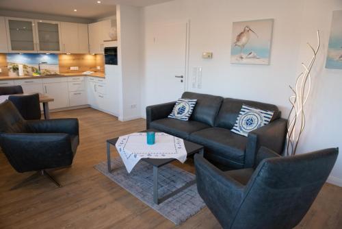 a living room with a couch and chairs and a table at Mole links in Norddeich