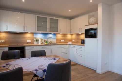 a kitchen with white cabinets and a table with chairs at Mole links in Norddeich