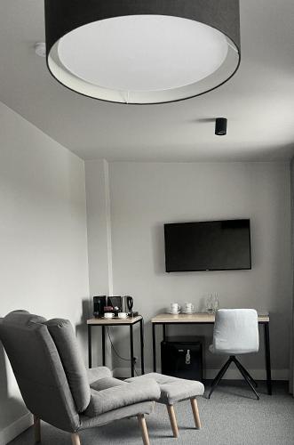 a living room with a chair and a flat screen tv at Kamienica nr 6 in Aleksandrów Łódzki
