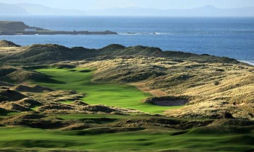 a golf course with the ocean in the background at Bluebell Cottage Portrush in Portrush